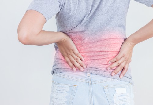 Portrait of young woman touching her back with pained expression, suffering from backache after long working hours, Healthy concept.